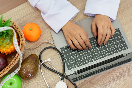 Nutritionist using laptop with stethoscope and fresh fruits for AI healthcare and digital nutrition consultation