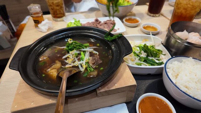 Adding Fresh Morning Glory to Hot Thai Beef Soup in Bangkok