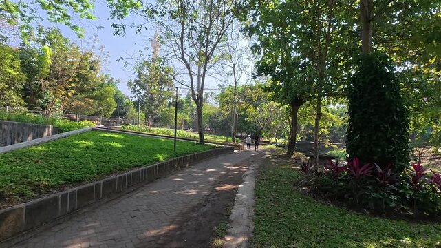 Green urban park pathway surrounded by trees in Yogyakarta