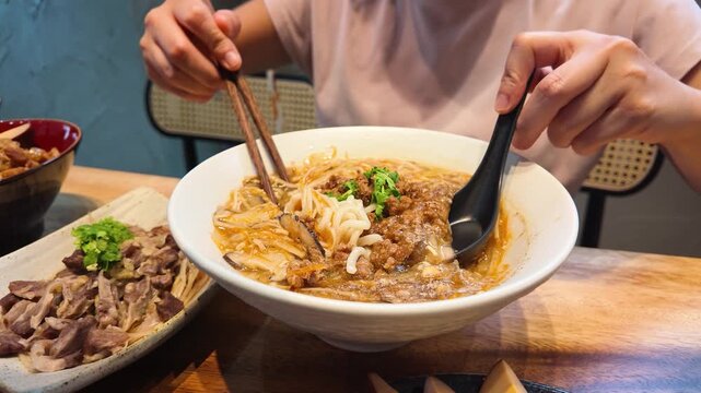 Person Eating Spicy Hot and Sour Noodle Soup with Minced Pork