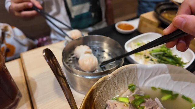 Person Using Chopsticks to Pick Up Dim Sum Dumplings