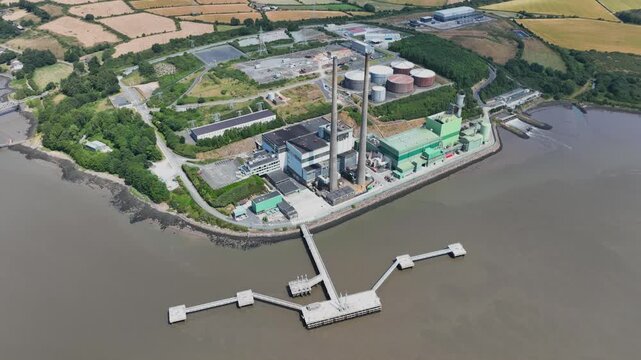 overview Stunning aerial perspective of electricity production facility beside the River Suir in Wexford, Ireland. Renewable power infrastructure framed by forests, fields and flowing water.