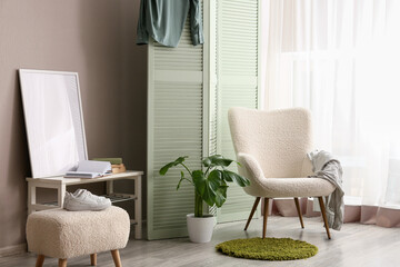Fototapeta premium Cozy living room interior with a comfortable armchair, green plant, and decorative screen, home decor