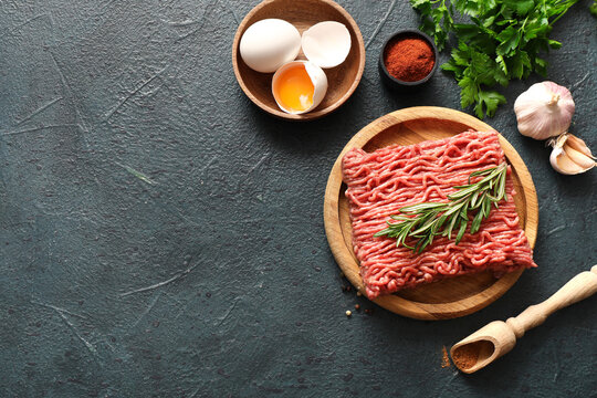 Plate with fresh ground meat, rosemary, eggs, parsley and garlic on green grunge background