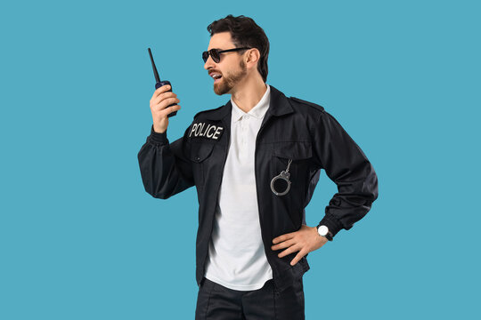 Male police officer with radio transmitter on blue background