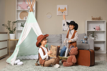Fototapeta premium Cute children dressed as cowboys with rocking horse reading adventure book at home