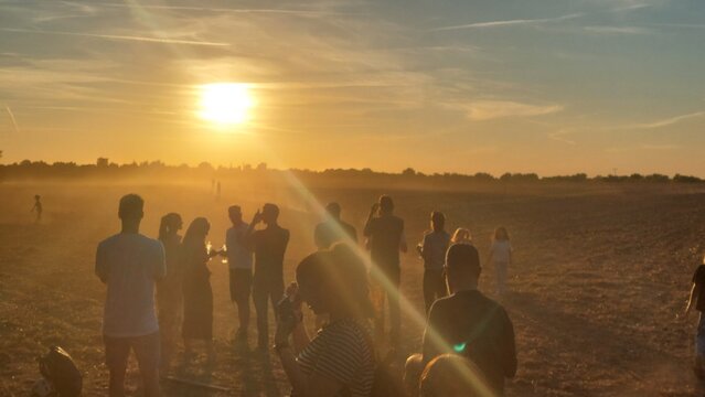 Gruppe von Zuschauern blickt auf einem staubigen Feld in den Sonnenuntergang der partiellen Sonnenfinsternis