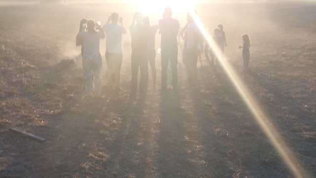 Gruppe von Zuschauern blickt auf einem staubigen Feld in den Sonnenuntergang der partiellen Sonnenfinsternis