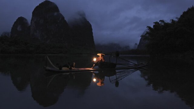 View of cormorant fisherman on Li River at dusk, China.