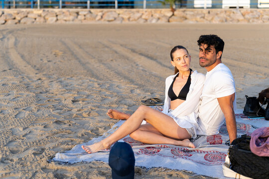Couple relaxing on beach blanket, enjoying peaceful winter sunset together