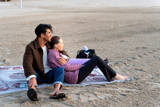 Couple relaxing on beach during winter, enjoying a peaceful moment together