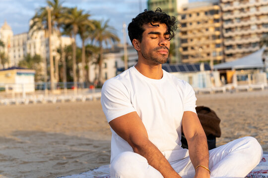 Young man meditating on a beach during winter, practicing mindfulness and relaxation