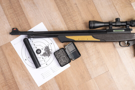 Flat Lay of Scoped Air Gun Barrel with Open Ammunition Box and Bullseye Target