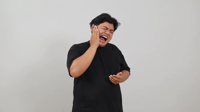 Young Asian overweight man isolated on white background having a strong teeth pain