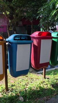 Colorful recycling bins standing beside green park in Yogyakarta