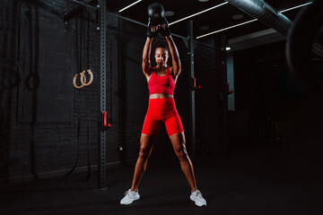 Fototapeta premium Fit young woman in red sport outfit making workout in the gym