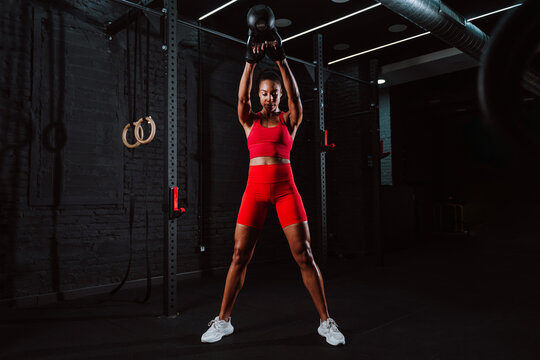 Fit young woman in red sport outfit making workout in the gym