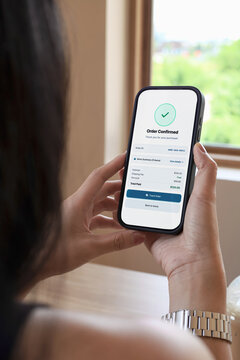 Woman holding smartphone showing order confirmed screen with check mark. Concept of online shopping, mobile payment success, and e-commerce application.