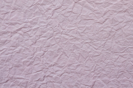 Crumpled pale pink paper texture with wrinkled creased surface for creative design