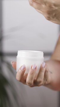 Woman hands holding cosmetic jar and unscrewing lid in close up vertical slow motio