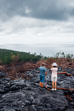 Couple de touristes sur une coul&eacute;e de lave &agrave; l'&icirc;le de La R&eacute;union. Visiter les coul&eacute;es de lave. Touristes &agrave; La R&eacute;union. Vacances sous les Tropiques.