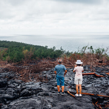 Couple de touristes sur une coul&eacute;e de lave &agrave; l'&icirc;le de La R&eacute;union. Visiter les coul&eacute;es de lave. Touristes &agrave; La R&eacute;union. Vacances sous les Tropiques.