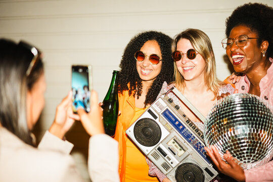 Group of multiracial girls having fun together dancing listening music while taking video reel with a smartphone outdoor - Party and nightlife concept - Focus on blond girl face - UGC content