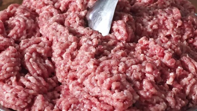 Close-up of raw ground pork with a metal spoon, showing fresh minced meat texture and food preparation. Concept of cooking, protein, meat products and everyday nutrition.