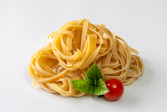 Fresh tagliatelle pasta nest served with a vibrant basil leaf and ripe cherry tomato on a clean white background.