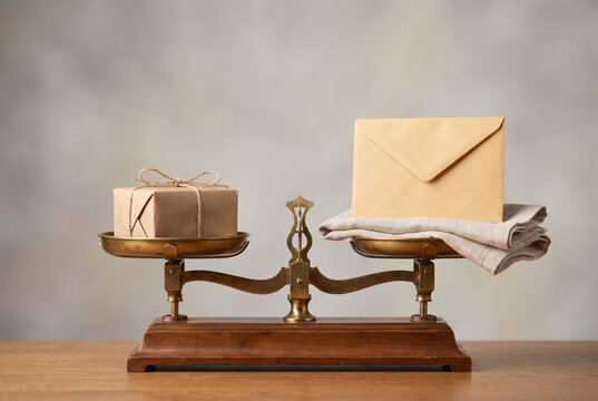 Balance scale displays a package and an envelope with cloth in an indoor setting