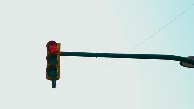 Red traffic light changing to green at city intersection in daylight. Signal transition allowing vehicles to proceed through Spanish streets. Urban transportation and road control system