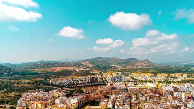 Sagunto cityscape from elevated viewpoint with Mediterranean farmland and mountain ridges. Timelapse with fast moving clouds over historic Spanish town. Scenic time lapse panorama in Valencia region