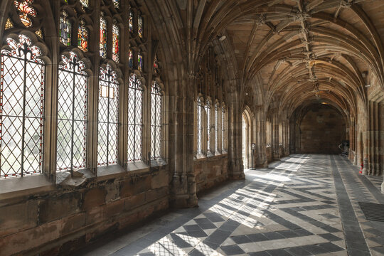 Worcester, United Kingdom - 21 July 2026: View of the historic cloisters at Worcester Cathedral with intricate stone vaulted ceilings, stained glass windows, and a patterned tiled floor.