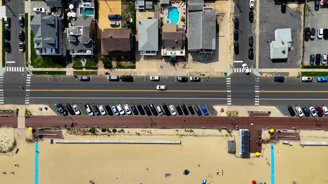 Birds-eye aerial of Belmar beach, boardwalk, busy street and sunny coastal town