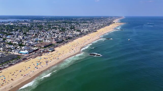 Aerial wide shot of a crowded Belmar Beach on a beautiful sunny summer day with waves