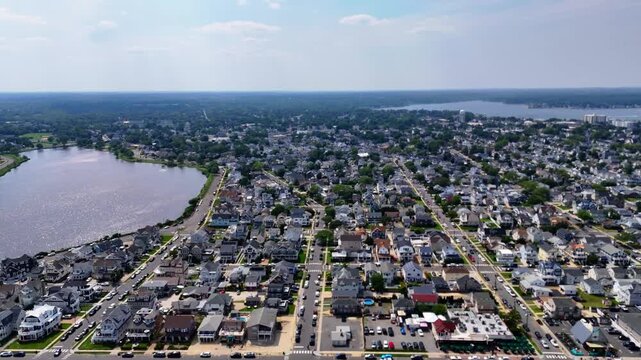 Aerial pull-back shot revealing Belmar beach, ocean and coastal town on a sunny day
