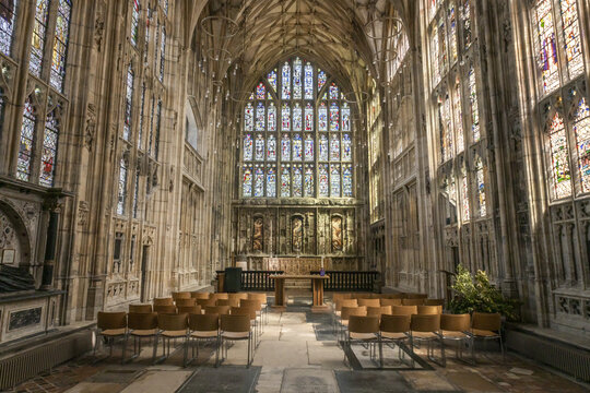 Gloucester, United Kingdom - 21 July 2026: View of the interior of Gloucester Cathedral with its ornate stained glass windows, stone vaulted ceiling, and rows of wooden chairs.