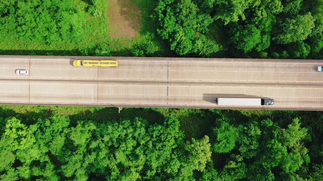 Comprehensive top down bird's eye view of the Interstate 10 Atchafalaya Basin Bridge, highlighting commercial logistics trucks and lush forests.