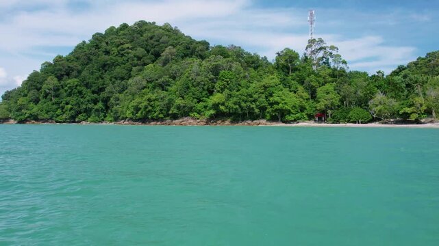 Smooth cinematic drone footage creating a beautiful parallax effect as a lush tropical shoreline slowly recedes behind vibrant turquoise waters.