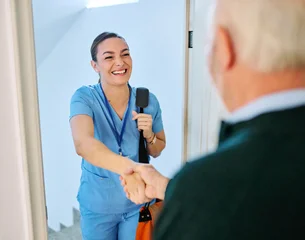 Doctor or nurse caregiver with senior man at home or nursing home, a caregiver standing on the front door arriving and being welcomed by a senior woman © Lumos sp