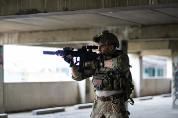 Fototapeta premium Armed tactical soldier aiming assault rifle during urban military operation inside building wearing camouflage uniform with night vision gear for defense mission