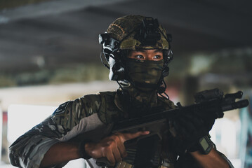 Fototapeta premium Special force soldier holding combat rifle inside building wearing camouflage uniform face mask tactical helmet headset gear during urban operation