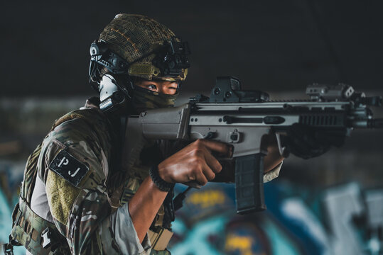Military commando soldier aiming rifle wearing camouflage uniform tactical helmet headset mask gear inside building during urban combat operation