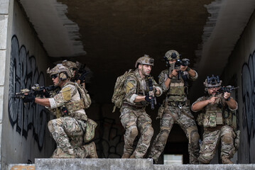 Fototapeta premium Special force soldier team in camouflage gear aim rifle inside urban building during military operation training mission