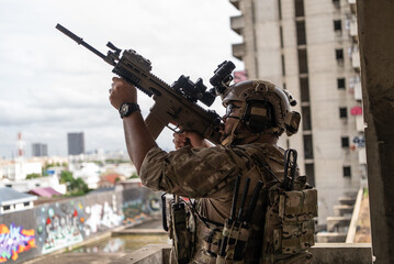 Fototapeta premium Tactical special force soldier aiming rifle weapon near window during sniper urban combat operation in high building