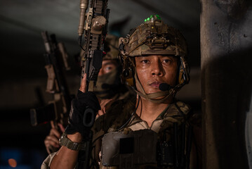 Fototapeta premium Close up portrait of special force soldier holding assault rifle weapon with helmet during tactical military combat operation