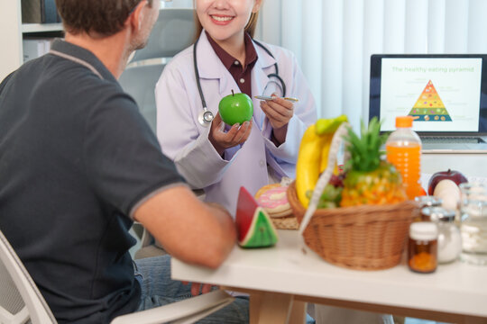 Female nutrition consultant showing green apple to male patient during health consultation