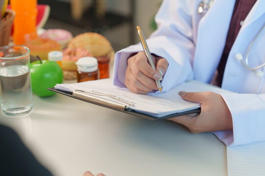 Nutrition consultant writing health summary notes on clipboard during patient consultation