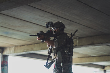 Fototapeta premium Armed tactical soldier aiming assault rifle during urban military operation inside building wearing camouflage uniform with night vision gear for defense mission