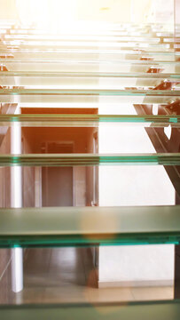 Modern architectural design of glass staircase with metal supports leading upwards to bright light, contemporary interior building structure, abstract perspective vertical photo